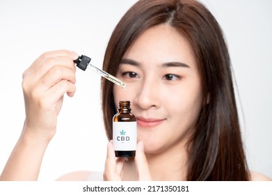 Close Up Asian Woman Looks At A Bottle Of CBD Oil. Sleep Supplement. Medical Marijuana. Vitamins And Supplements Healthy Alternatives.