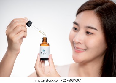 Close Up Asian Woman Looks At A Bottle Of CBD Oil. Sleep Supplement. Medical Marijuana. Vitamins And Supplements Healthy Alternatives.
