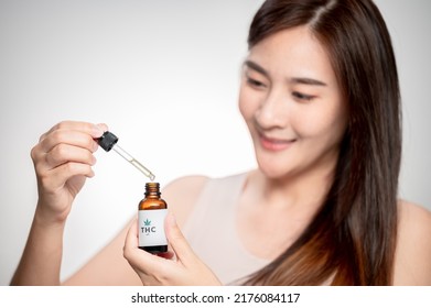 Close Up Asian Woman Looks At A Bottle Of CBD Oil. Sleep Supplement. Medical Marijuana. Vitamins And Supplements Healthy Alternatives.
