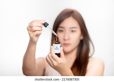 Close Up Asian Woman Looks At A Bottle Of CBD Oil. Sleep Supplement. Medical Marijuana. Vitamins And Supplements Healthy Alternatives.
