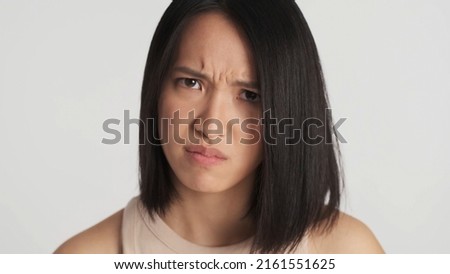 Close up Asian woman offended on boyfriend looking angry at camera isolated over white background. Irate face expression