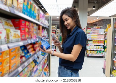 Close Up Of Asian Woman Is Shopping For Product And Scanning Barcode With Smartphone At Supermarket.