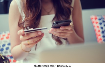 close up asian woman using smartphone devices for shopping online in website store and payment by credit card in living room , lifestyle people concept