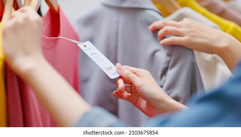 close up of asian women looking at clothes and price tag while shopping at store