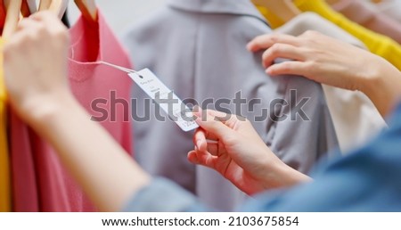 close up of asian women looking at clothes and price tag while shopping at store