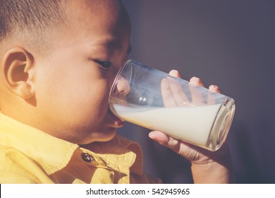 Close Up Of Asian Young Boy Drinking Milk. Side View