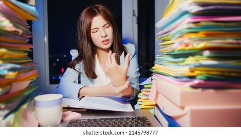 close up of asian young businesswoman has wrist pain while working overtime with laptop and documents in office - Shutterstock ID 2145798777