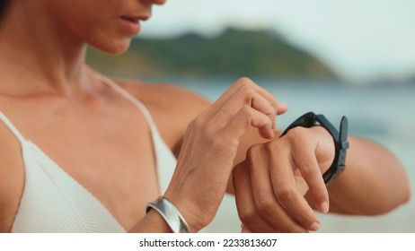 Close up asian young fitness woman look at smartwatch at sunlight outdoor at the beach in summer. athlete workout equipment. Female touching screen on watch entering app. Sport technology - Powered by Shutterstock