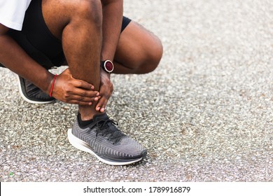 Close Up Asian Young Sport Runner Black Man Wear Watch Hands Joint Hold Leg Pain Because Of Twisted Ankle Broken While Running At The Outdoor Street Health Park, Healthy Exercise Injury From Workout