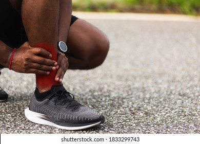 Close Up Asian Young Sport Runner Black Man Wear Watch Hands Joint Hold Leg Pain Because Of Twisted Ankle Broken While Running At The Outdoor Street Health Park, Healthy Exercise Injury From Workout