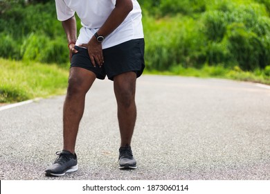 Close Up Asian Young Sport Runner Black Man Wear Watch Hands Joint Hold Leg She Has Thigh Pain While Running At The Outdoor Street Health Park, Healthy Exercise Injury Muscle From Workout Concept