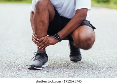 Close Up Asian Young Sport Runner Black Man Wear Watch Hands Joint Hold Leg Pain Because Of Twisted Ankle Broken While Running At The Outdoor Street Health Park, Healthy Exercise Injury From Workout