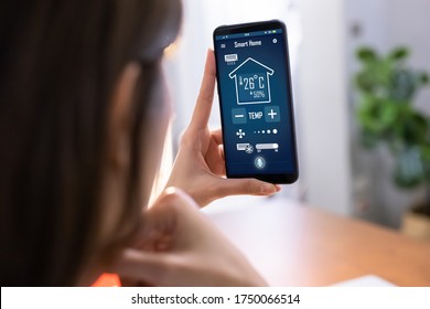 Close Up Of Asian Young Woman Using Smart Home App On Mobile Phone To Control Air Conditioner Temperature