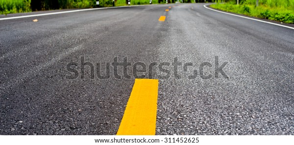 Close up\
asphalt surface of road divide yellow\
lines