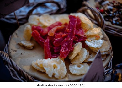 Close up of assorted dried fruit including pineapple rings and red candied strips arranged in a basket at a market stall in Civita di Bagnoregio, Italy.