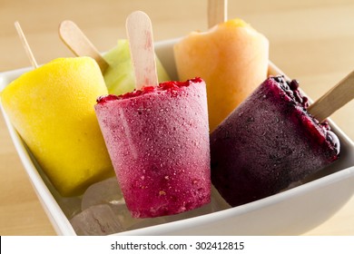 Close up of assorted flavors of homemade fresh pureed frozen fruit popsicles in white bowl with ice - Powered by Shutterstock