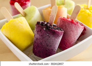 Close up of assorted flavors of homemade fresh pureed frozen fruit popsicles in white bowl with ice - Powered by Shutterstock