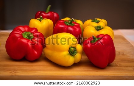Close up of assorted red and yellow bell peppers placed on a cutting board in the kitchen. Also known as Sweet pepper, Pepper or Capsicum.