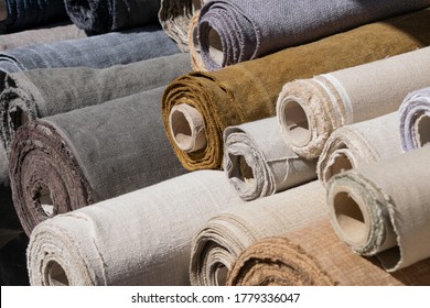 Close Up Assorted Rolls Of White, Beige And Brown Flax Linen Fabric And Canvas Textile On Retail Market Stall, High Angle View