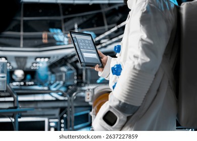 Close up of astronaut using tablet to view spacecraft analytics during scientific mission. Spaceship crew member in spacesuit looking at orbital navigation data on device during planetary exploration