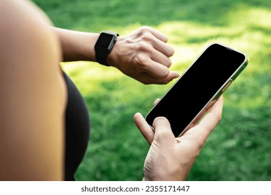 Close up of athlete holds a mobile phone in his hands and tracks the results of training on a smartwatch. - Powered by Shutterstock