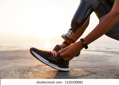 Close up of athlete woman with prosthetic leg tying shoelace outdoor at the beach - Powered by Shutterstock