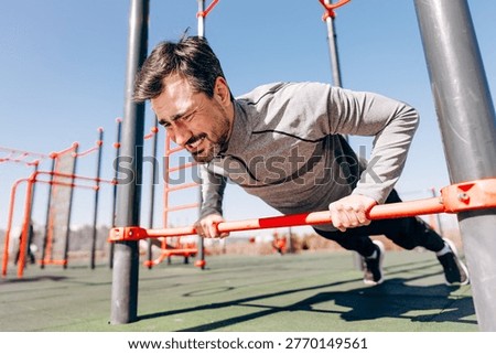 Close up of athletic man performing push ups on fitness bars. Strength workout, endurance training and healthy lifestyle