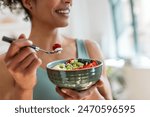 Close up of athletic woman eating a healthy fruit bowl in the kitchen at home