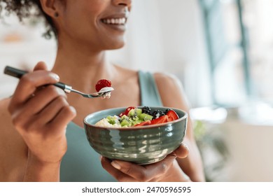 Close up of athletic woman eating a healthy fruit bowl in the kitchen at home - Powered by Shutterstock