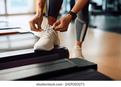 Close up of athletic woman tying shoelace on sneakers while preparing for workout at health club. - Powered by Shutterstock