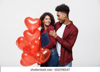 Close up attractive African American couple huging and holding red heart balloon.