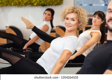 Close up of attractive and slim middle aged women who is practicing Pilates with her friends at gym. Fitness - concept of healthy lifestyle. Fitness people in the gym. - Powered by Shutterstock