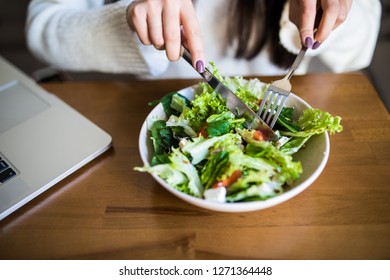 Close up attractive woman hand holding fork and spoon to eating vegetable salad at lunch in cafe.