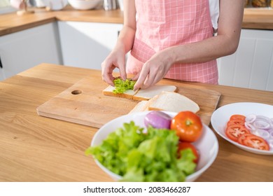 Close Up Of Attractive Woman Making Sandwich For Breakfast In Morning. Beautiful Girl Wear Apron Enjoy Eat Clean Vegetables Healthy Food For Health Care In House. Diet Lose Weight And Foods Concept.