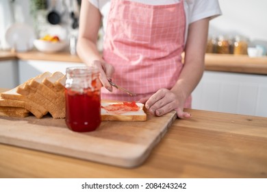 Close Up Of Attractive Woman Making Sandwich For Breakfast In Morning. Beautiful Girl Wear Apron Enjoy Spread Jam On Bread To Eat Healthy Food For Health In House. Diet Lose Weight And Foods Concept.