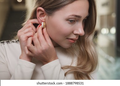 Close Up Of An Attractive Woman Putting On Diamond Earrings