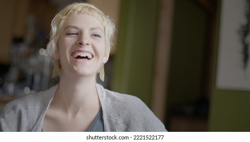 Close Up Of Attractive Young Woman With Short Blonde Hair Laughing During A Conversation In An Urban Loft.