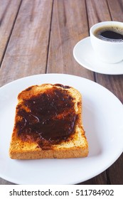 Close up of Australian breakfast with savory spread on a sliced wholewheat toast and black coffee on a wooden table.