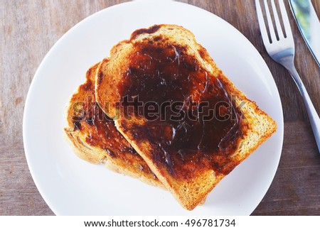 Close up of Australian breakfast with savory spread on a sliced wholewheat toast on a wooden table.