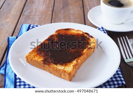 Close up of Australian breakfast with vegemite spread on a sliced wholewheat toast on a wooden table.