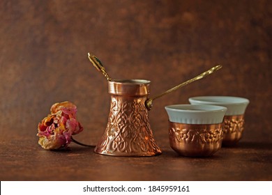 Close Up Authentic Handmade Coffee Set, Engraved Coffe Pot  
And Two Cups, Bosnian Coffee Set With Dry Rose Beside Isolated On Brown Background