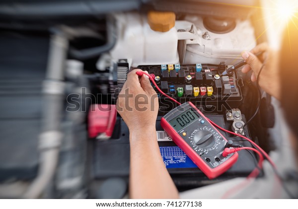 Close up of auto mechanic\
jumping battery car,check voltage level car battery,helping\
concept.