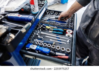 Close up of an auto-mechanic picking fools from toolbox at mechanic's workshop. - Powered by Shutterstock