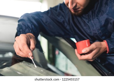 Close up Automobile glazier worker fixing and repair windscreen or windshield of a car in auto service station garage - Powered by Shutterstock