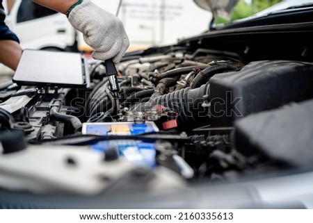 Close up of automotive mechanics using application on the digital tablet to check engine in the engine room, auto maintenance service concept.