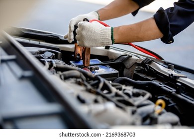 Close up of automotive mechanics using jump leads for jump-starting automotive batteries when suffering from a discharged battery in the garage, checking and maintenance service concept.