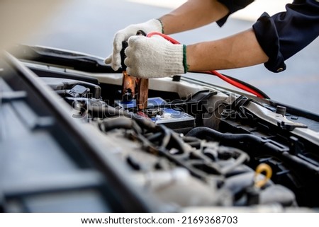 Close up of automotive mechanics using jump leads for jump-starting automotive batteries when suffering from a discharged battery in the garage, checking and maintenance service concept.