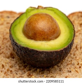 Close Up Of An Avacado Cwith A Seed Cut In Half On A Piece Of Toast On A White Plate 