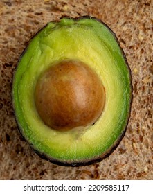 Close Up Of An Avacado Cwith A Seed Cut In Half On A Piece Of Toast On A White Plate 