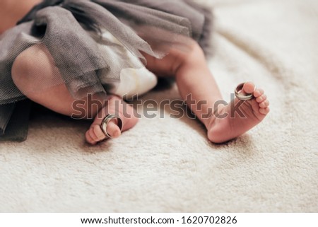 Close up of babie's feets with her parent's wedding rings on her toes